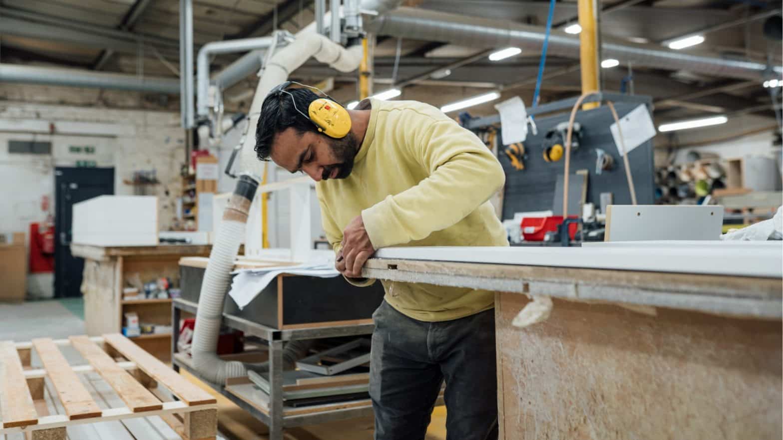 Skilled craftsman inspecting custom woodwork in a professional workshop environment.
